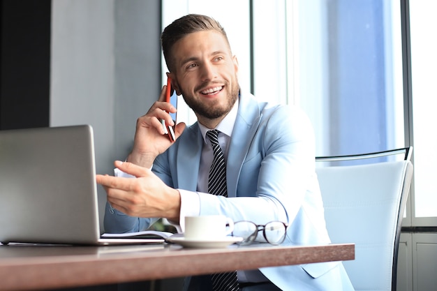 Uomo d'affari che utilizza il suo telefono cellulare in ufficio.