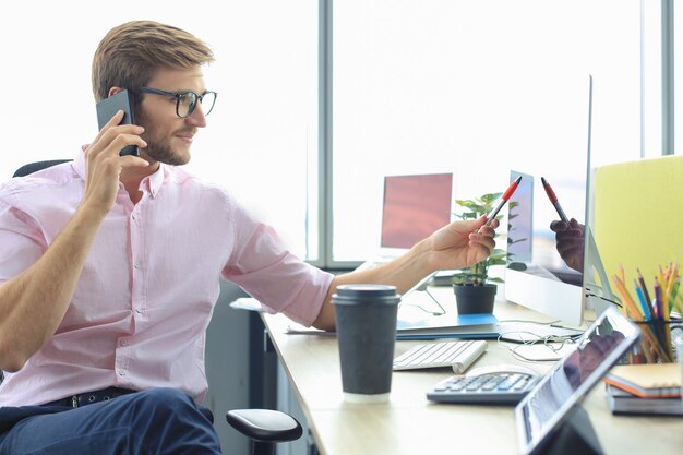 Uomo d'affari che utilizza il suo telefono cellulare in ufficio.