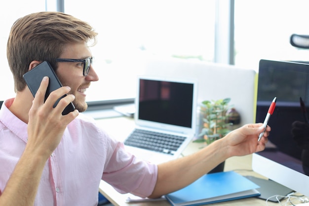 Uomo d'affari che utilizza il suo telefono cellulare in ufficio.