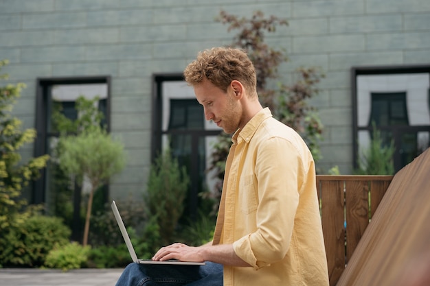 Uomo d'affari che utilizza un computer portatile che lavora online per strada studente universitario che studia