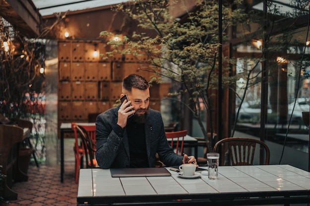 Uomo d'affari che utilizza uno smartphone in un caffè