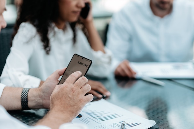 Uomo d'affari che utilizza uno smartphone mentre si lavora con documenti finanziari