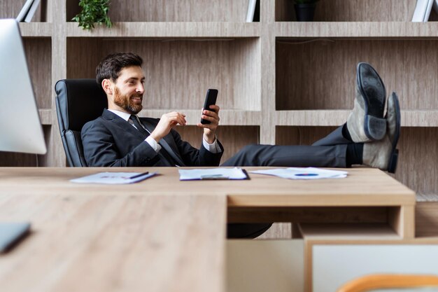 Uomo d'affari con abito elegante seduto alla scrivania del computer in ufficio