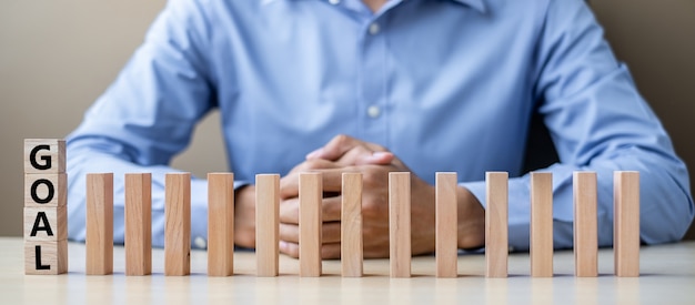 Uomo d&#39;affari con i blocchetti o domino di legno di GOAL. Attività commerciale