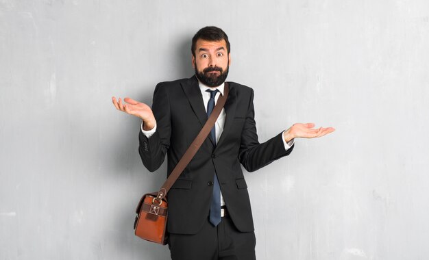 Uomo d&#39;affari con la barba che ha dubbi mentre alzando le mani e le spalle