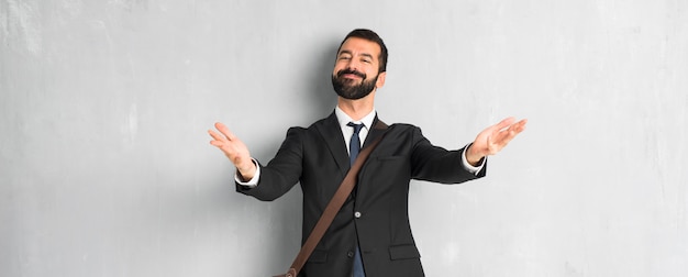 Uomo d&#39;affari con la barba che presenta e che invita a venire con la mano