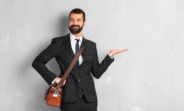 Uomo d&#39;affari con la barba che tiene copyspace immaginario sul palmo per inserire un annuncio