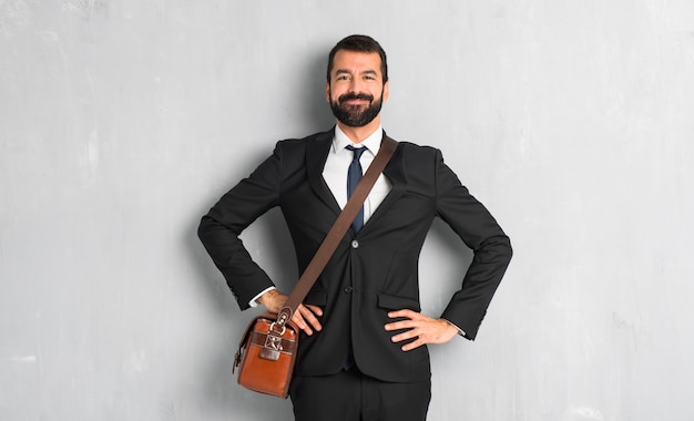 Uomo d&#39;affari con la barba in posa con le braccia all&#39;anca e ridendo guardando verso la parte anteriore