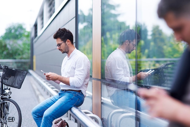 Uomo d'affari con la bicicletta tramite telefono cellulare all'aperto