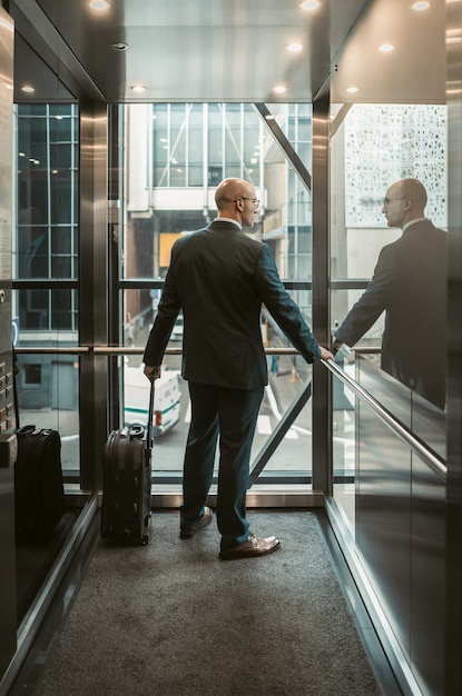 Uomo d'affari con la valigia nel centro business. Concetto di viaggio d'affari. Sguardi caucasici di mezza età dell'uomo