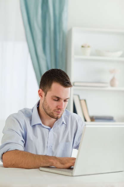 Uomo d&#39;affari con le maniche arrotolate che lavora al suo computer portatile