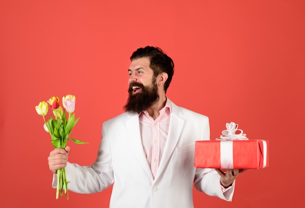 Uomo d'affari con regalo e bouquet di tulipani per il compleanno di san valentino bell'uomo tiene una confezione regalo