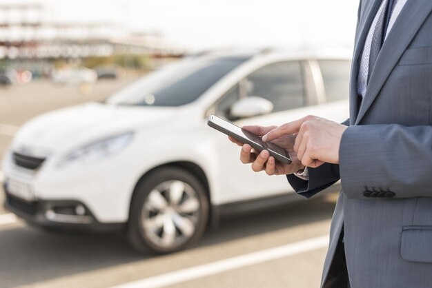 uomo d'affari con smartphone davanti all'auto alta qualità e risoluzione bel concetto di foto