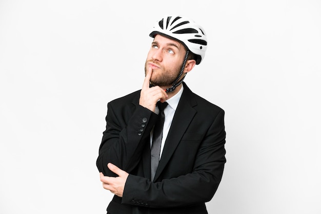 Uomo d'affari con un casco da bici su sfondo bianco isolato che ha dubbi mentre guarda in alto