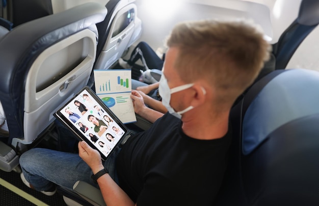 Uomo d'affari con un tablet e documenti in aereo