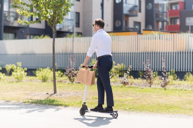 uomo d'affari con una borsa di carta da asporto che guida uno scooter