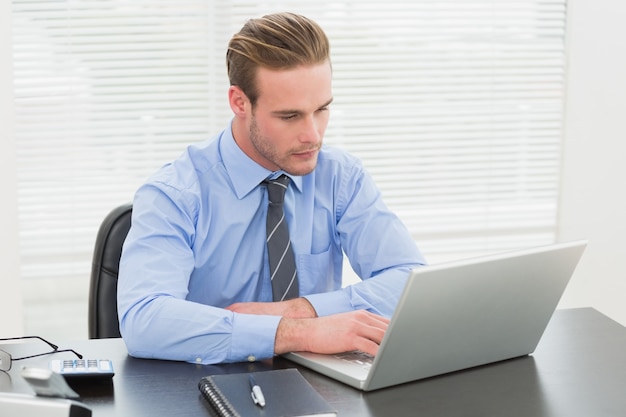 Uomo d&#39;affari concentrato che utilizza il suo computer portatile