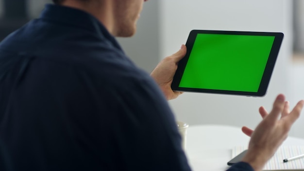 Uomo d'affari del primo piano che fa videochiamata sul tablet con chroma key al rallentatore Primo piano di un uomo che ha una conversazione video su una cella pad schermo verde