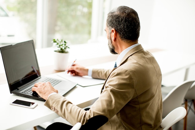 Uomo d&#39;affari di mezza età bello che lavora al computer portatile in ufficio moderno