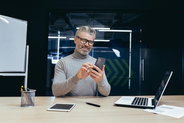 Uomo d'affari di successo maturo che lavora all'interno dell'ufficio Uomo d'affari dai capelli grigi anziano che usa il telefono