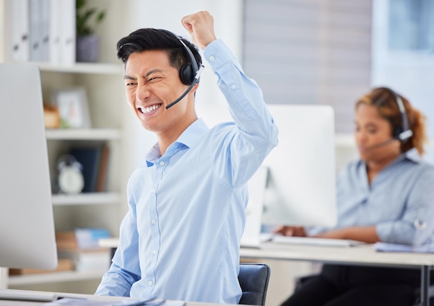 Uomo d'affari di telemarketing e allegria di successo del personale con buone notizie e promozione e-mail Motivazione contattaci e call center Impiegato asiatico con pugno e gesto vincente in ufficio con supporto