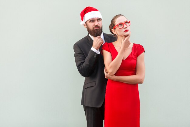 Uomo d'affari e donna ben vestiti che guardano lontano, toccano il mento e pensano. Foto in studio