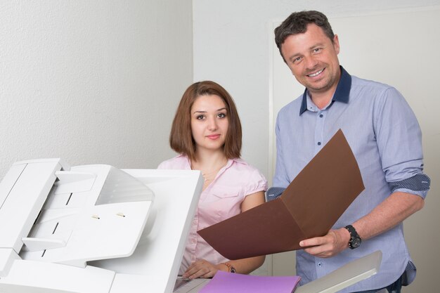 Uomo d'affari e donna che usando un sorridere della macchina della copia