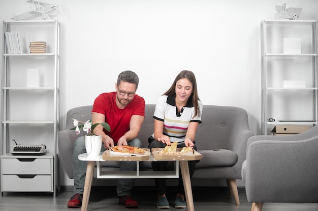 Uomo d'affari e donna d'affari che hanno una pausa pranzo in ufficio mangiando una fetta di pizza