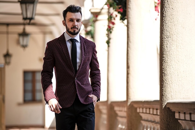 Uomo d'affari elegante e alla moda in giacca che cammina sul balcone di un edificio di architettura classica