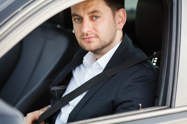 Uomo d'affari elegante vestito con il vestito allacciare la cintura di sicurezza prima di guidare la sua auto