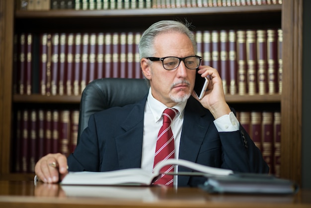 Uomo d&#39;affari facendo uso del suo telefono cellulare mentre leggendo il suo ordine del giorno