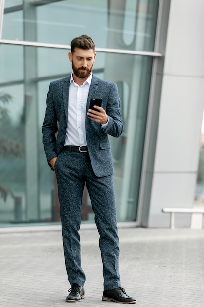 Uomo d'affari facendo uso dello smartphone e sorridendo all'aeroporto. Giovane uomo d'affari con il cellulare in aeroporto.