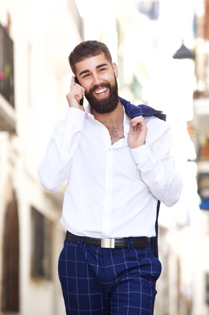 Uomo d&#39;affari felice che cammina in città e che parla sullo Smart Phone