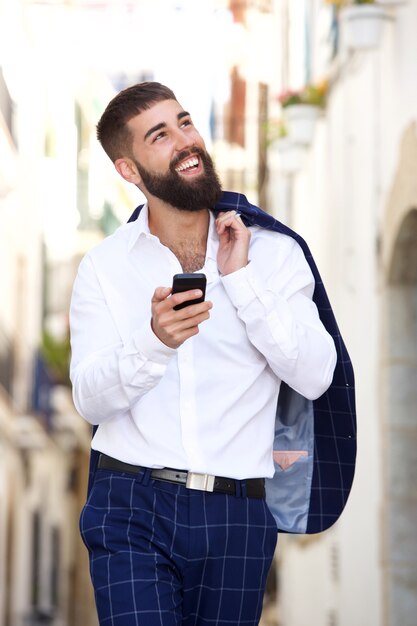 Uomo d&#39;affari felice che cammina sulla via con lo Smart Phone