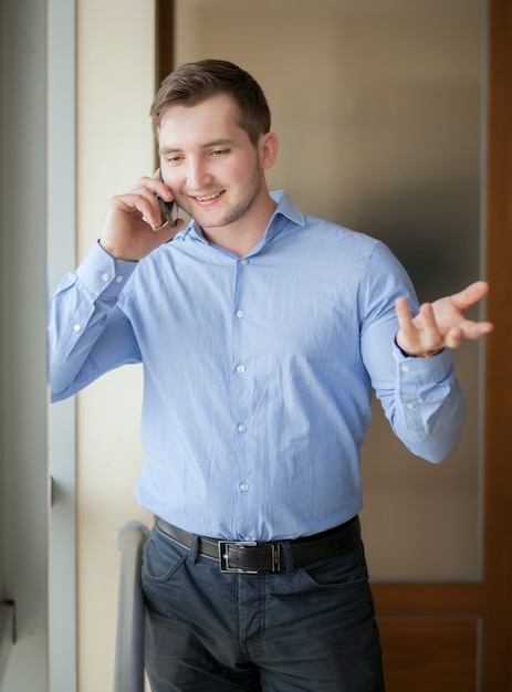 Uomo d'affari felice che parla sul telefono all'ufficio