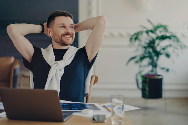 Uomo d'affari felice che riposa dopo il lavoro svolto nel suo accogliente posto di lavoro in un ufficio moderno