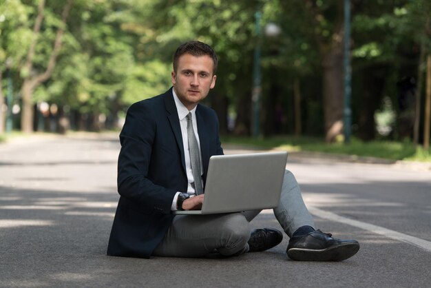 Uomo d'affari felice utilizzando Tablet Pc fuori su asfalto