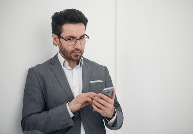 Uomo d'affari fiducioso che digita SMS sul tuo smartphonephoto con spazio di copia