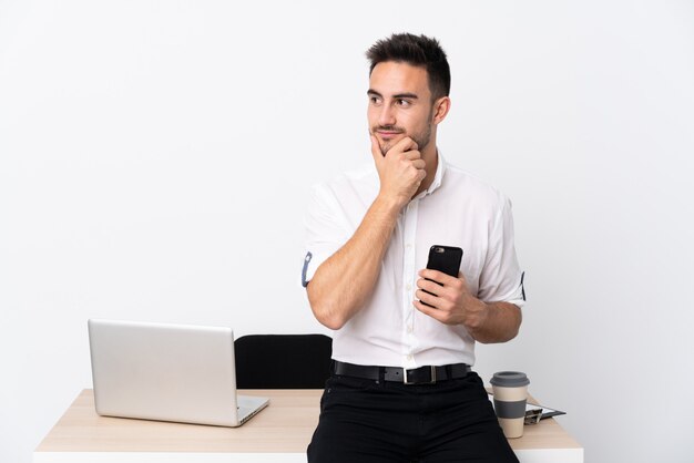 Uomo d'affari giovane con un telefono cellulare in un posto di lavoro pensando un'idea