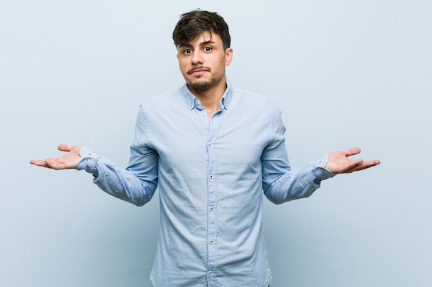 Uomo d'affari giovane dubitando e scrollando le spalle le spalle in gesto interrogativo.