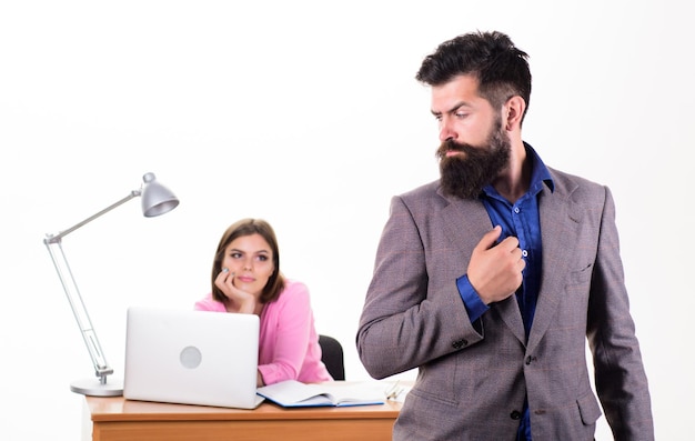 Uomo d'affari hipster Hipster con barba lunga in abbigliamento formale Hipster fiducioso e collega in ufficio Hipster barbuto con bella donna che lavora in background