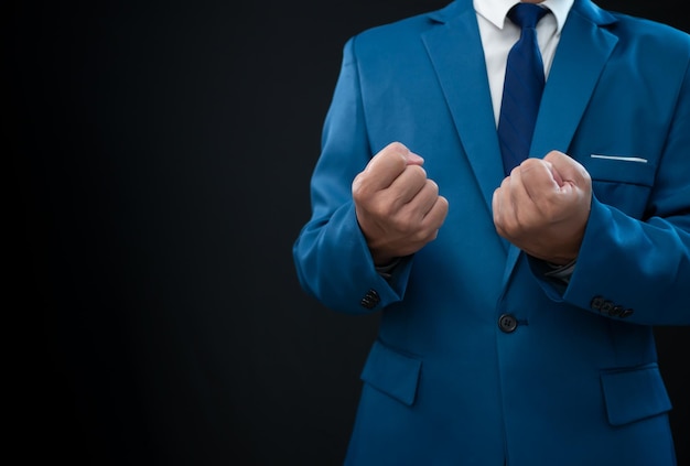 Uomo d'affari in abito blu e mostrando il pugno su uno sfondo fresco