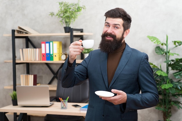 Uomo d'affari in abito formale Caffè del mattino Uomo felice e sicuro che usa il computer portatile Capo sul posto di lavoro Pausa caffè Uomo d'affari felice Uomo barbuto in ufficio Caffè del mattino felice Caposquadra