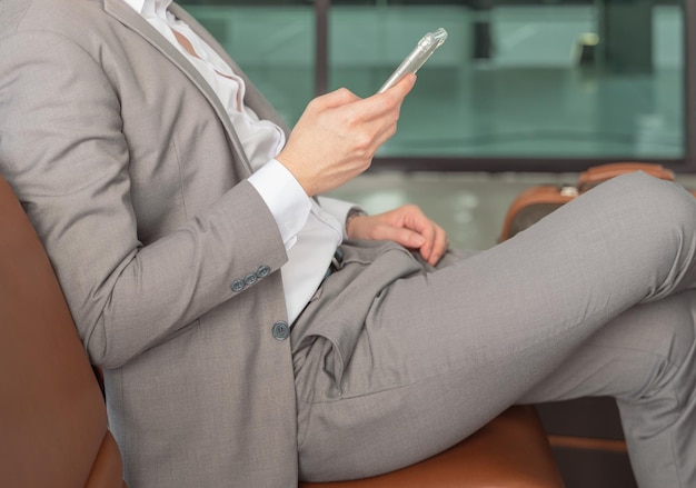 Uomo d'affari in attesa del volo nel terminal dell'aeroporto Uomo in tuta che lavora sul telefono cellulare