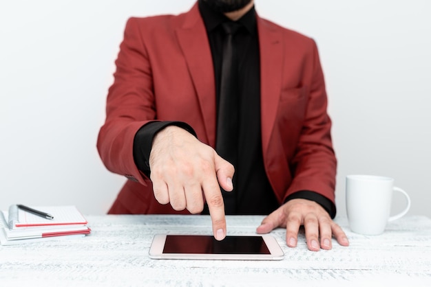 Uomo d'affari in giacca rossa seduto al tavolo e puntato con un dito sul messaggio importante sul cellulare Gentiluomo che mostra annuncio critico