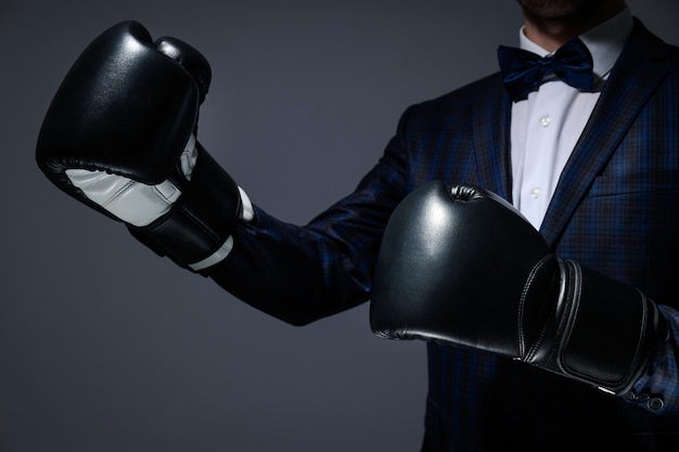 Uomo d'affari in guantoni da boxe su sfondo grigio scuro