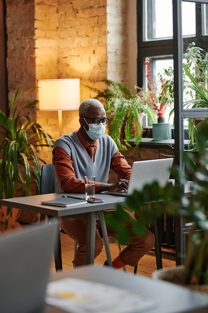 Uomo d'affari in maschera che lavora al computer portatile