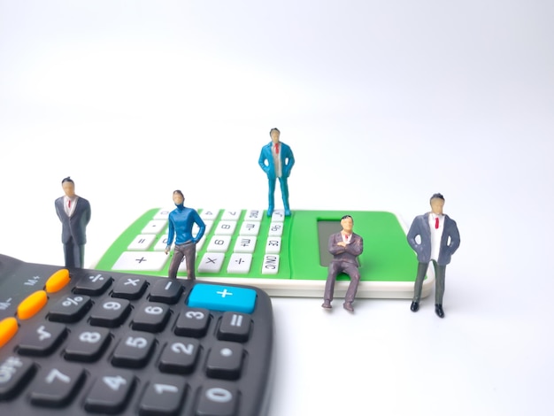 Uomo d'affari in miniatura con calcolatrice su sfondo bianco Idea di concetto di business
