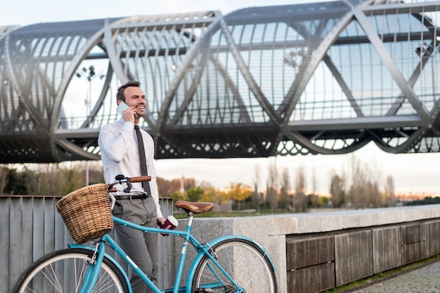 Uomo d'affari in piedi accanto alla sua bicicletta d'epoca che parla sulla folla