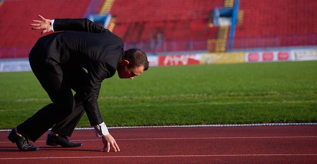 uomo d'affari in posizione di partenza pronto per correre e fare uno sprint su pista di atletica leggera